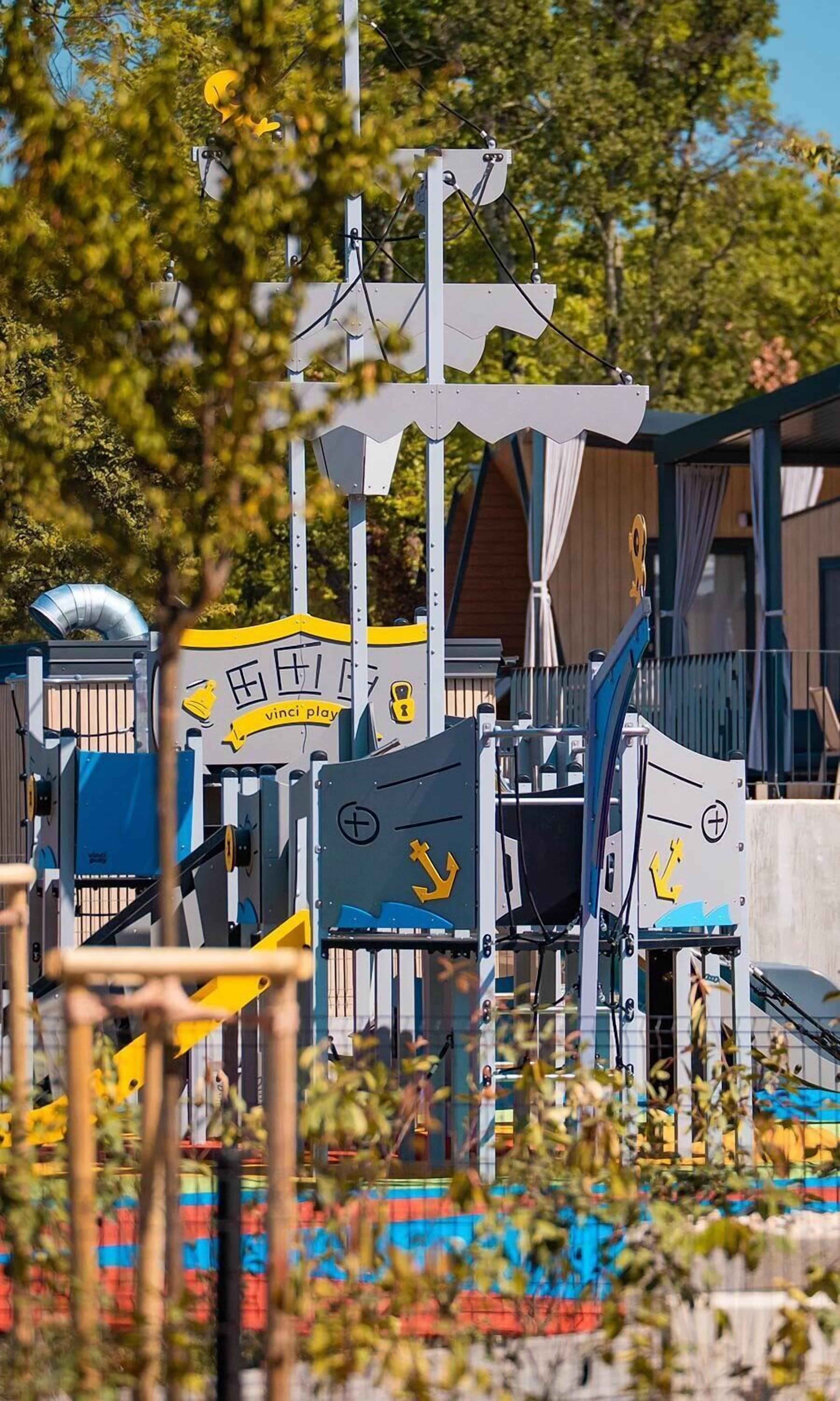 Ein Spielplatz mit verschiedenen Spielgeräten, darunter Rutschen und Kletterbereichen.