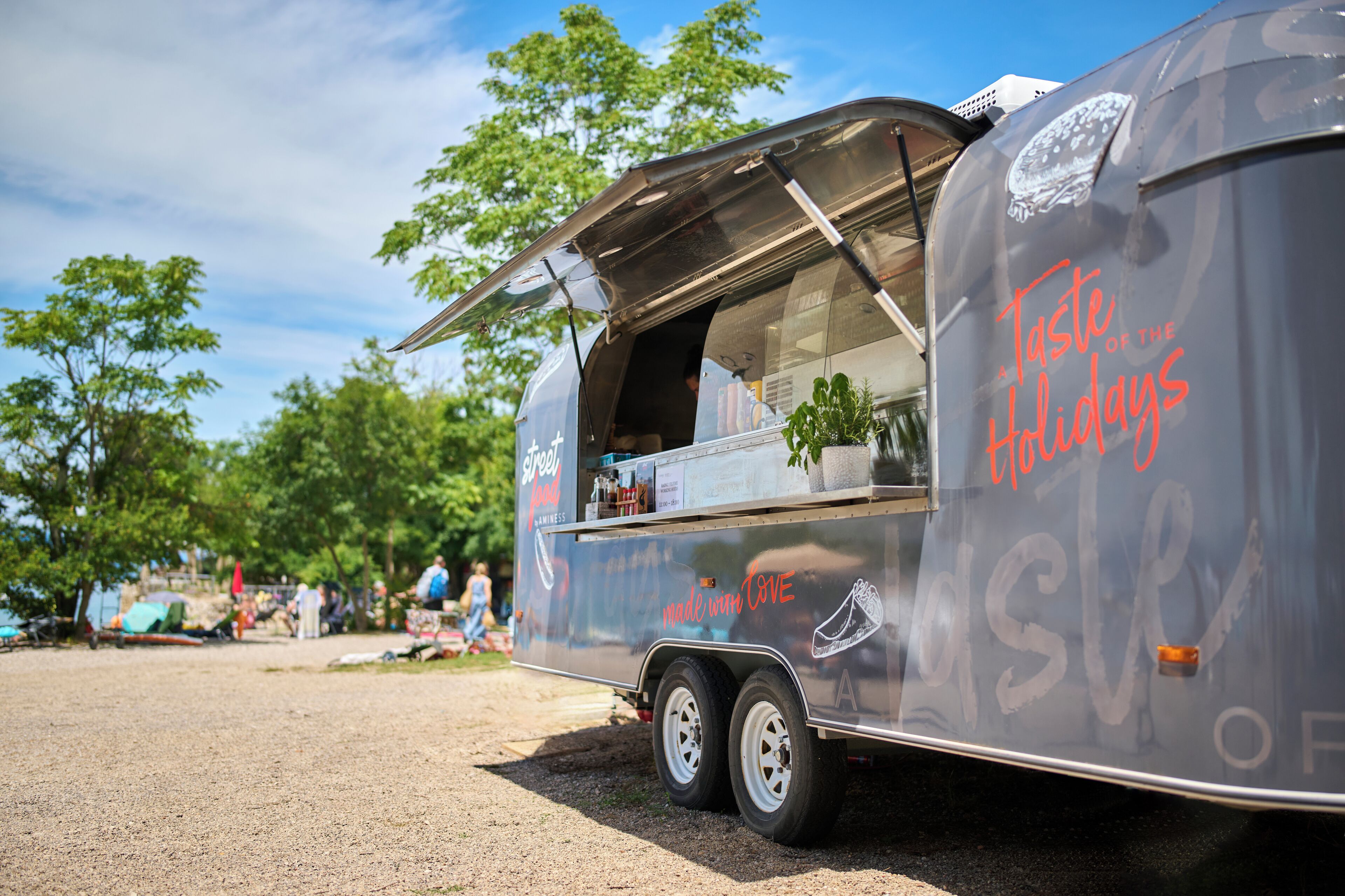 A food truck with a menu and a plant on the side.