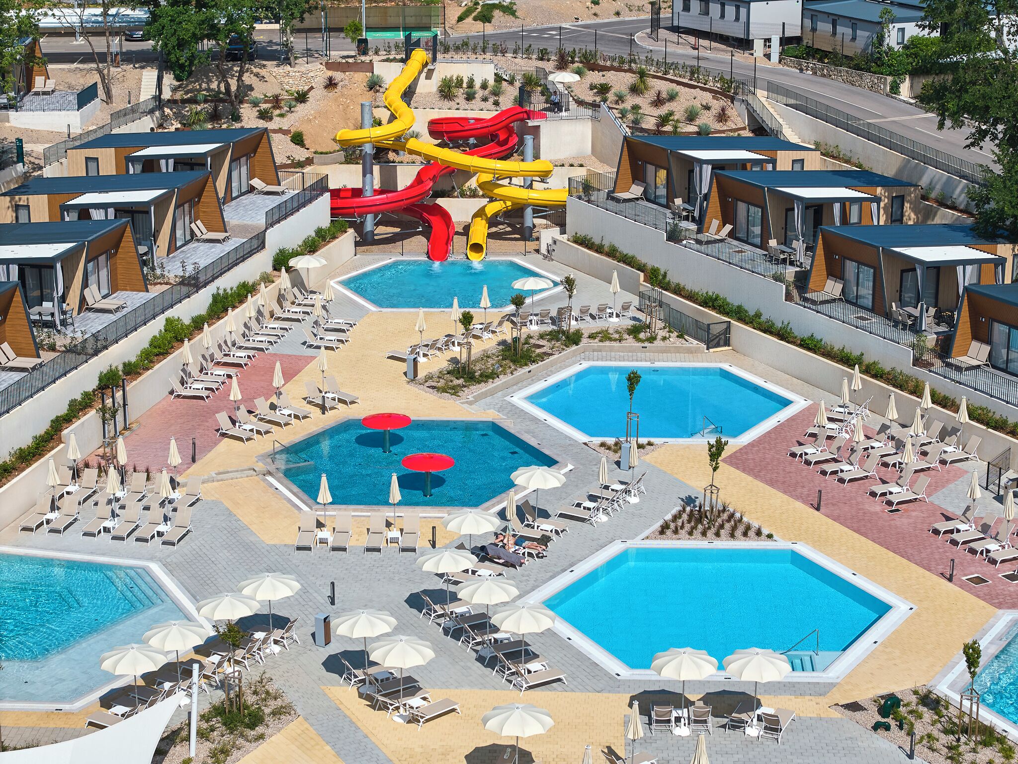 Ein Resort mit mehreren Schwimmbecken, Liegebereichen und einer Rutsche.