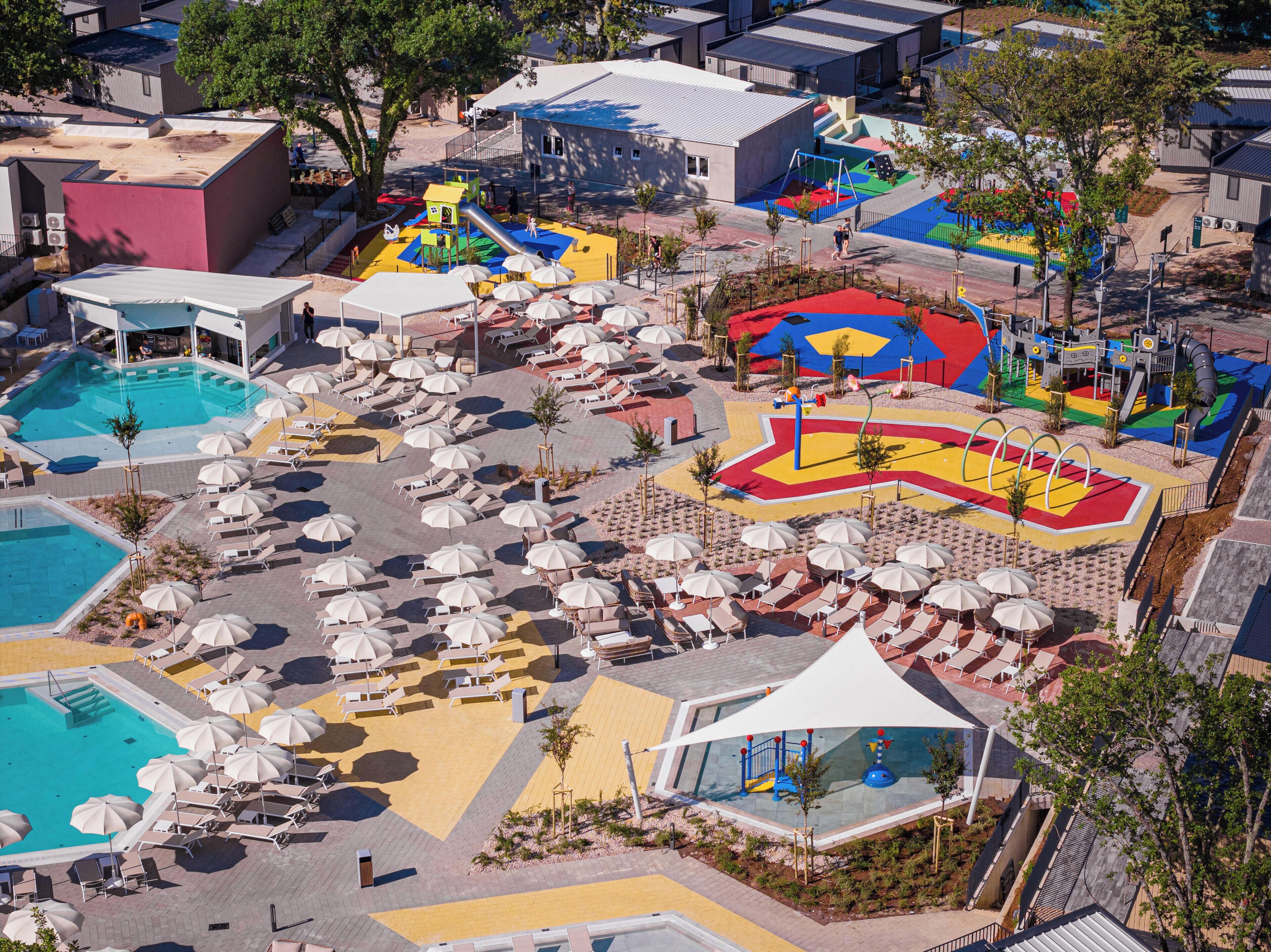 A resort with multiple swimming pools, sun loungers, and a children's play area.