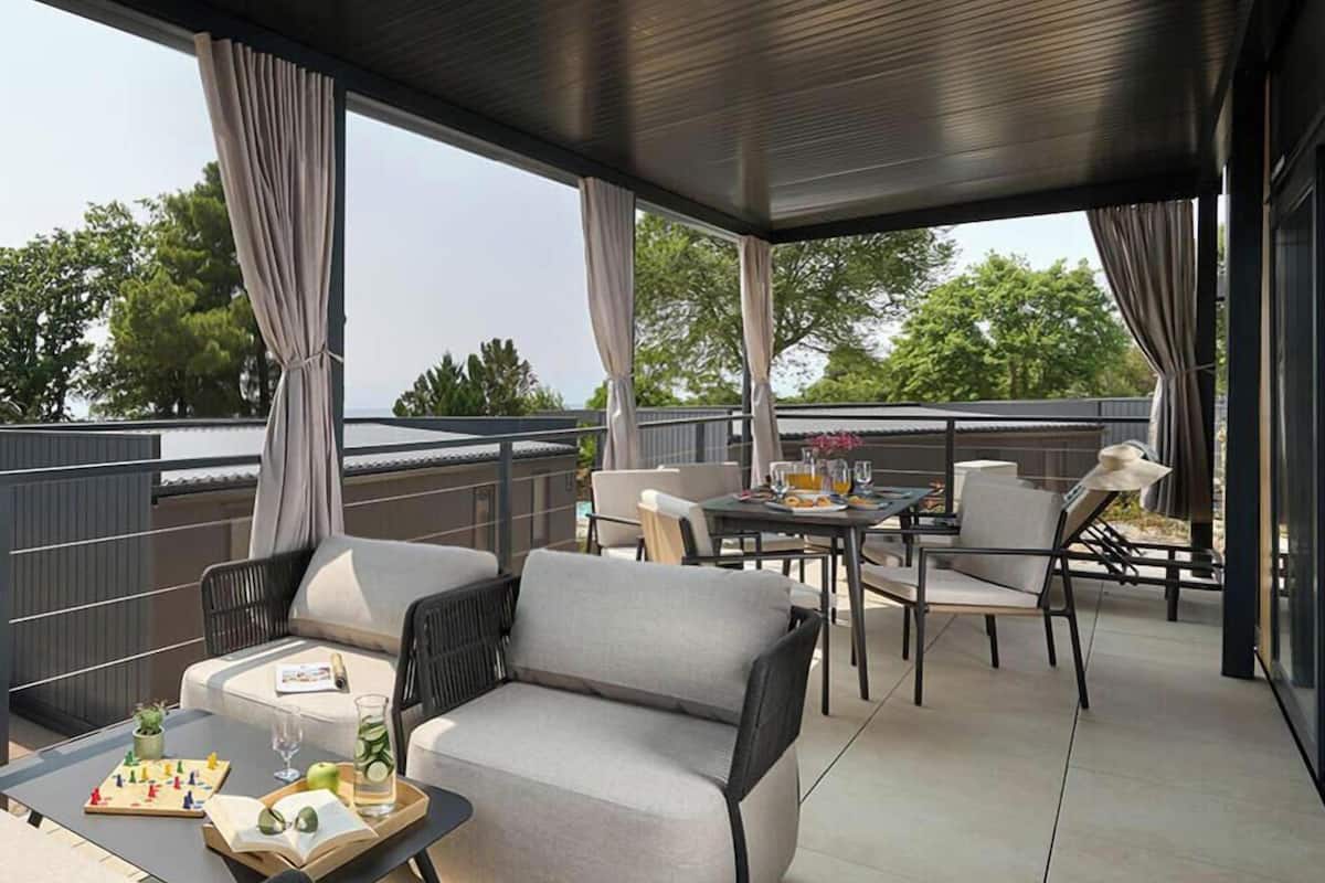 Un espace extérieur aménagé en terrasse, avec un canapé, des fauteuils et une table pour les repas.