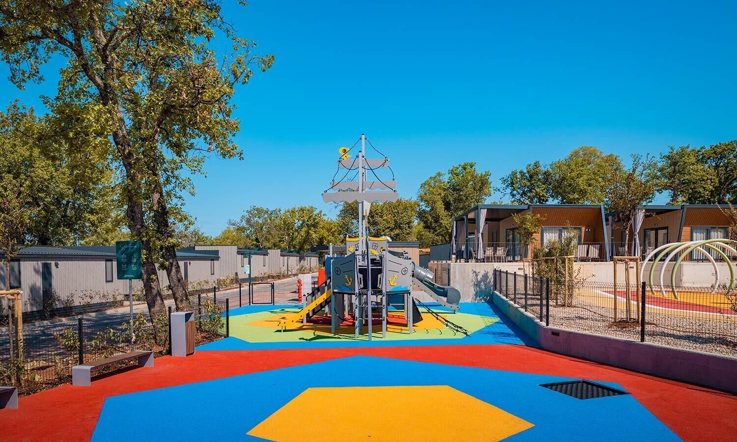 A playground with a slide, climbing structures, and a colorful play area.