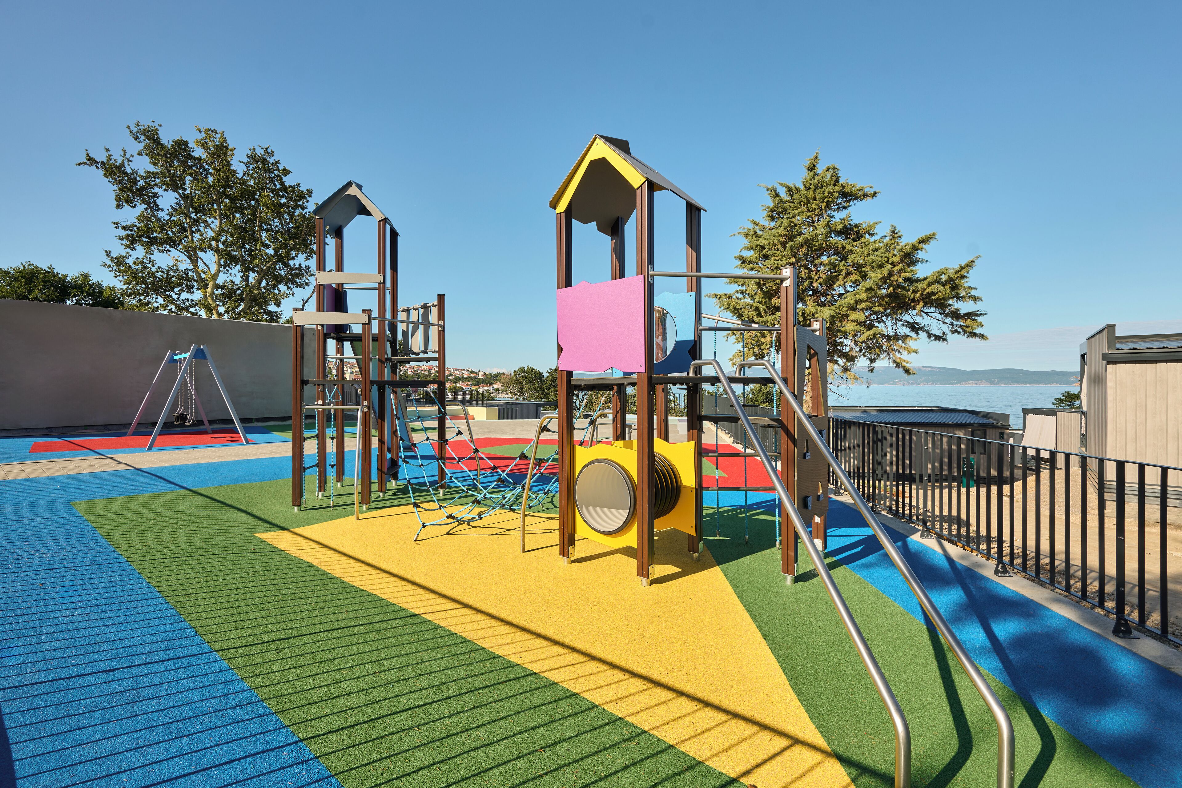 A playground with a climbing structure, a slide, and a fenced area.