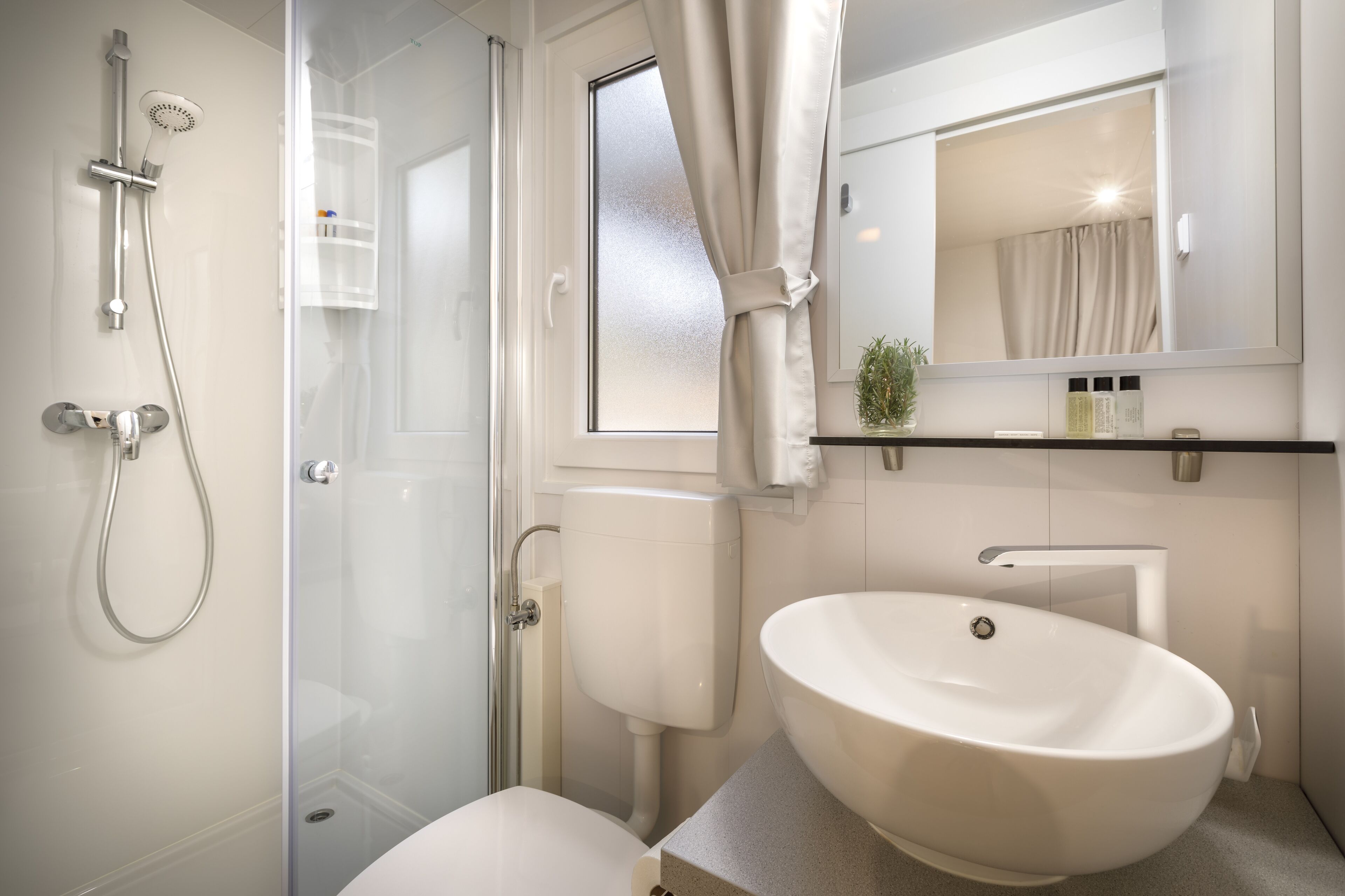 Un bagno moderno con cabina doccia in vetro, un WC bianco e un ampio lavabo con specchio sopra.
