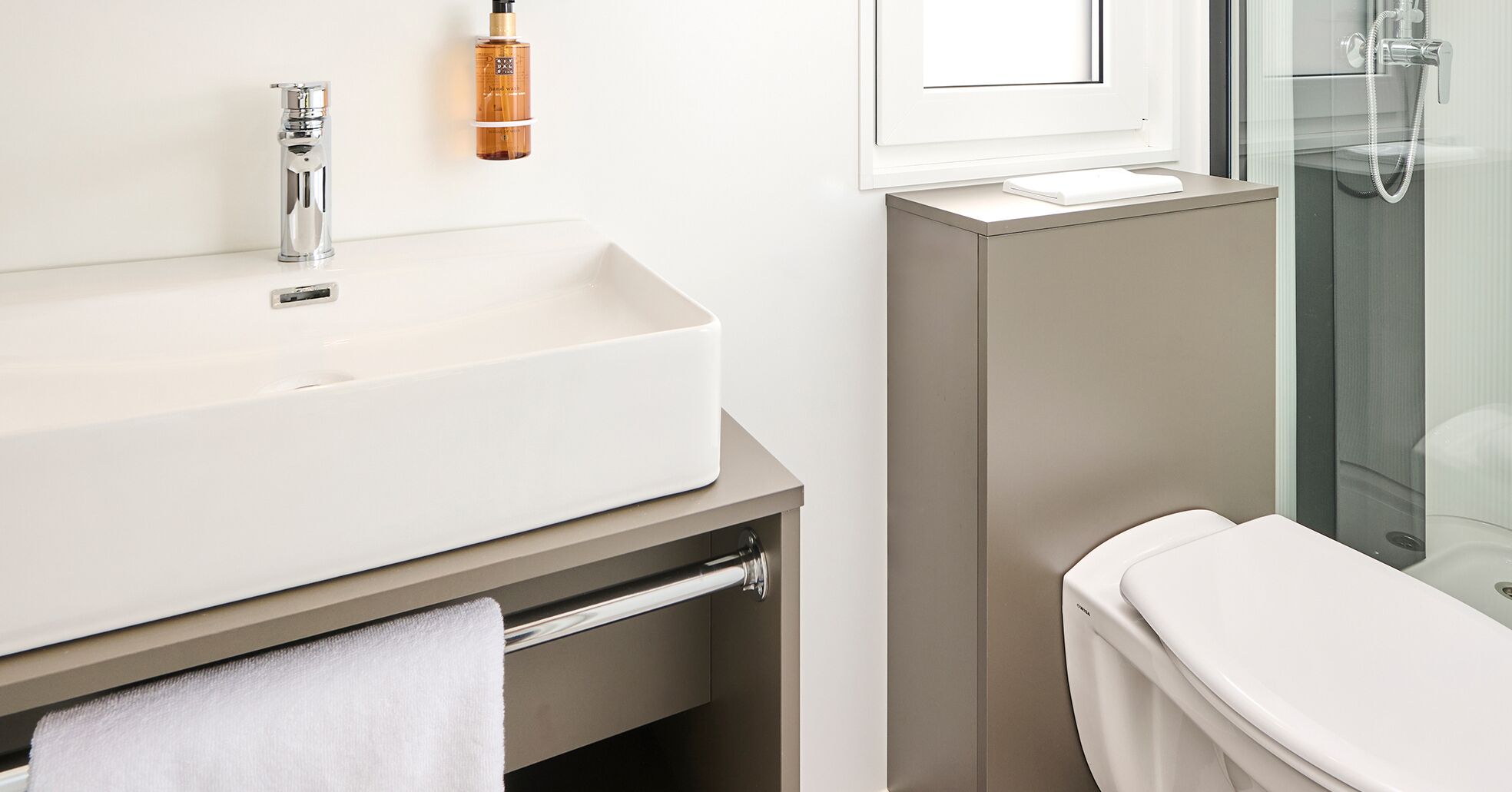 Et moderne badeværelse med en stor hvid vask, brusehoved og toilet.