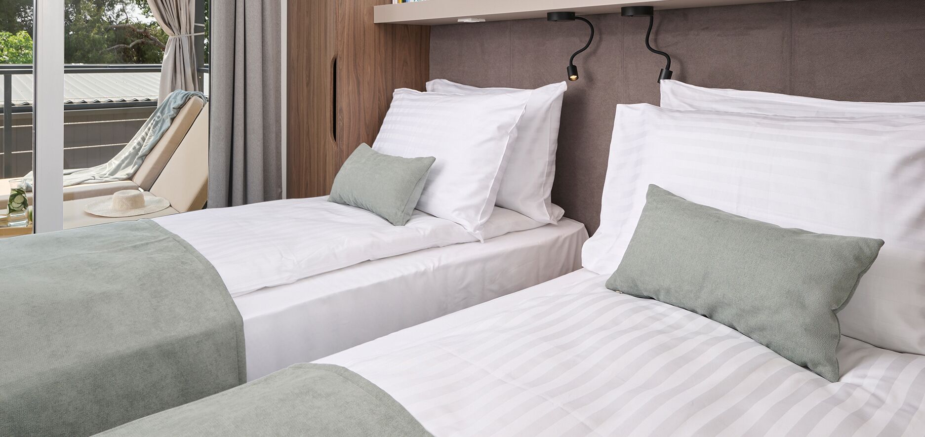 Habitación de hotel con dos camas, una ventana con cortinas y vistas al exterior.