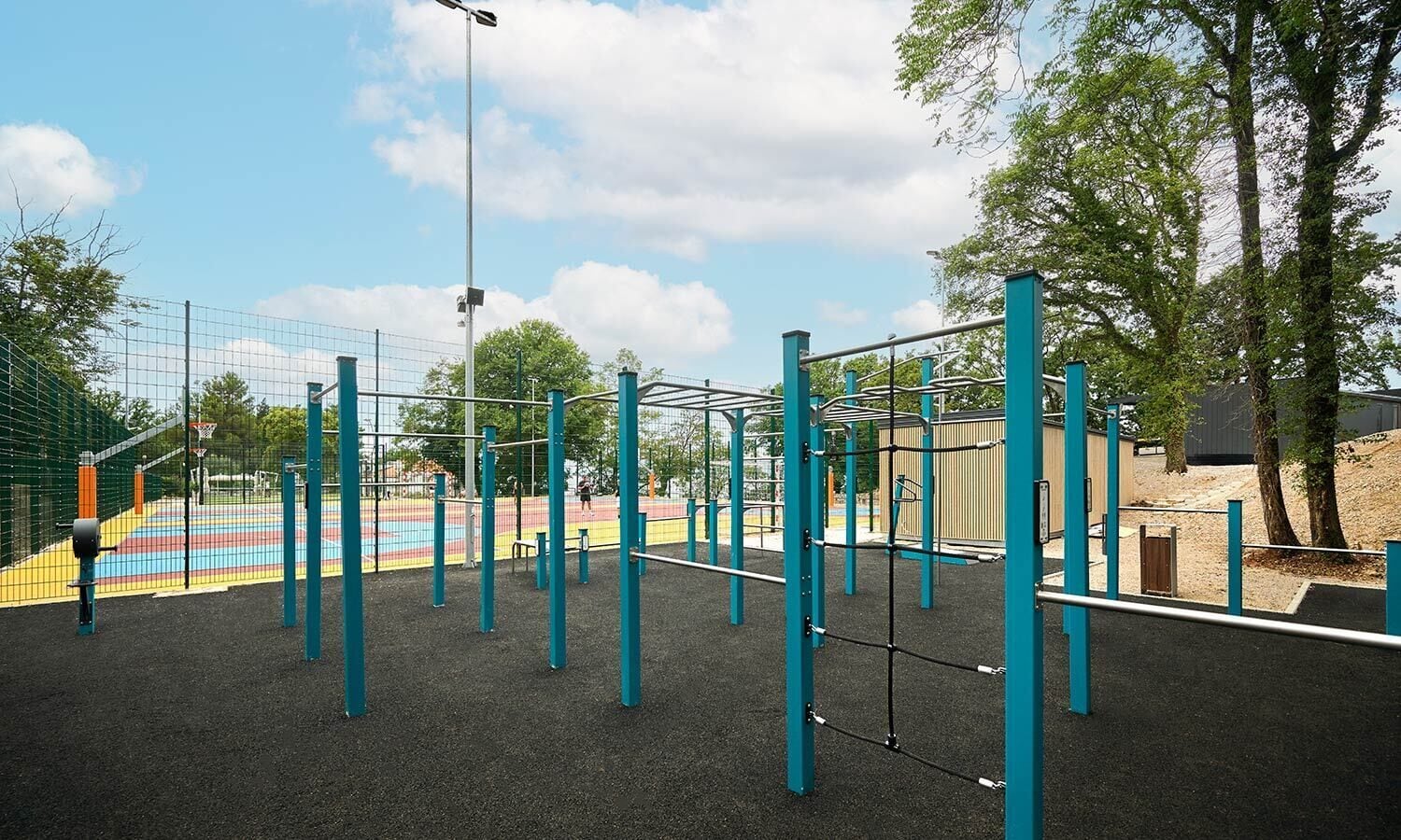 A playground with a basketball court, exercise equipment, and a fenced area.