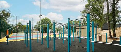 A playground with a basketball court, exercise equipment, and a fenced area.