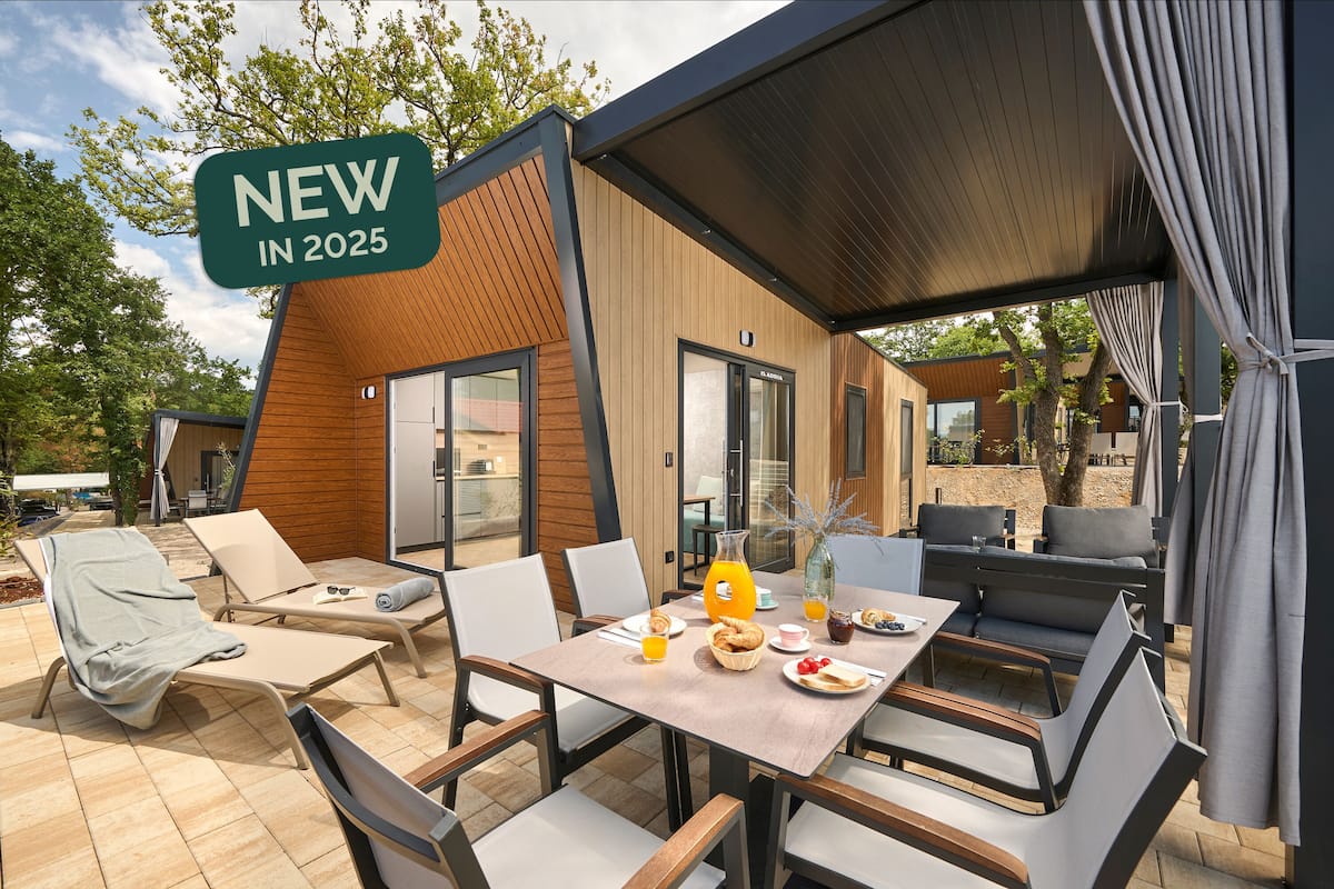 Un espace de restauration en plein air avec une table dressée pour deux personnes, entourée de chaises, et un panneau indiquant un nouveau projet en cours de développement, prévu pour 2025.
