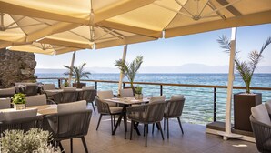 An outdoor seating area with tables and chairs, umbrellas, and a view of the sea. - Aminess Style Glamping Villas & Holiday Homes Atea (Omisalj)