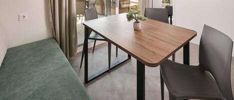 Un espace repas moderne avec une table en bois, des chaises noires et une petite plante en pot.