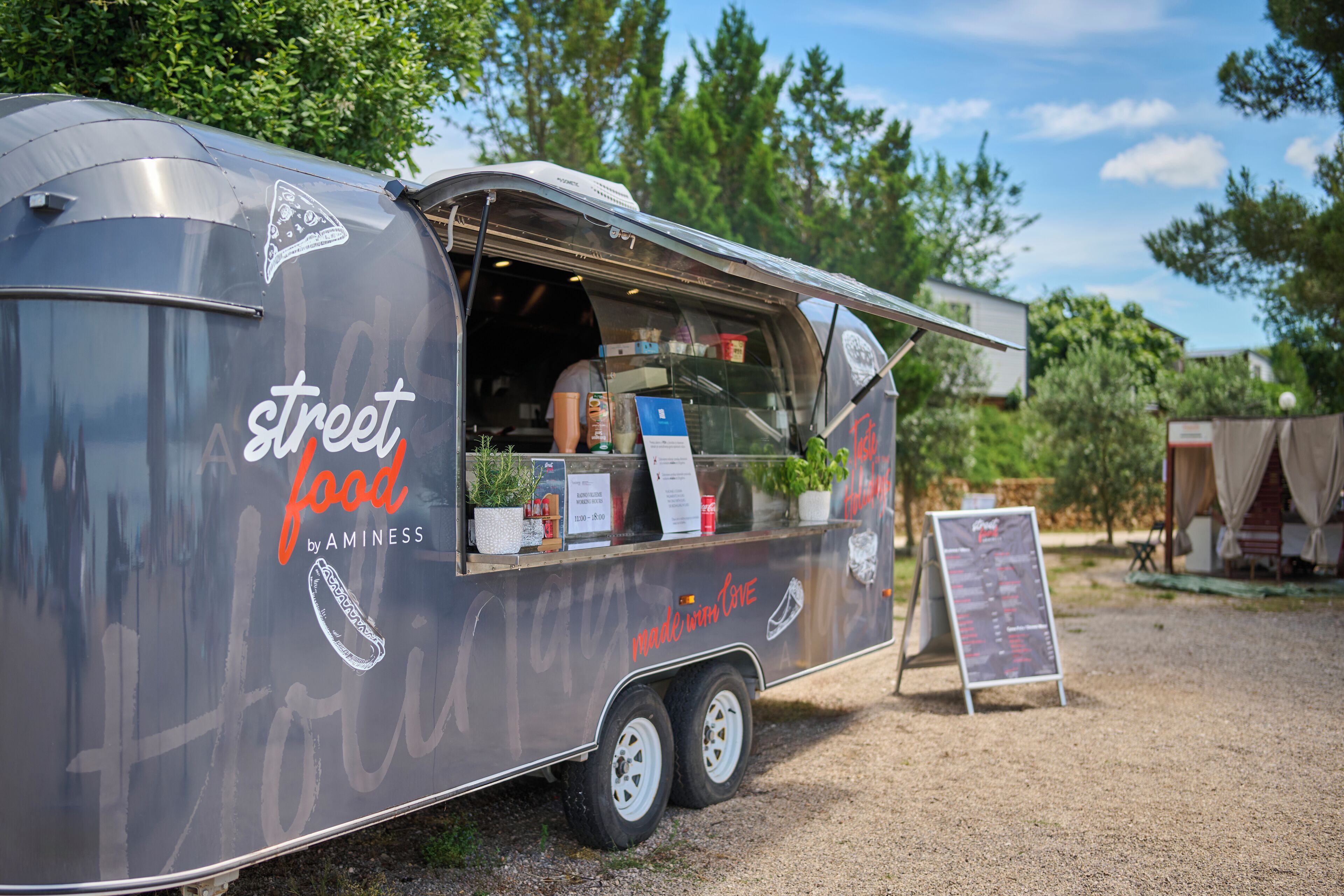 A street food trailer with a menu board and a signboard.