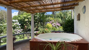 Un bain à remous sous une pergola en bambou, avec vue sur le jardin.