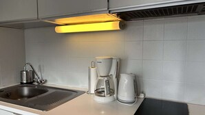A modern kitchen with a sink, a coffee maker, and a kettle.