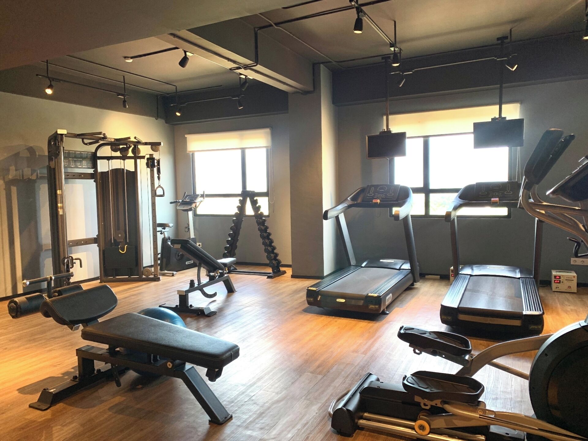 Ein Fitnessstudio mit verschiedenen Trainingsgeräten, darunter Laufbänder, Kraftgeräte und Kurzhanteln.