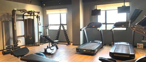 A gym with various exercise equipment including treadmills, weight machines, and dumbbells.