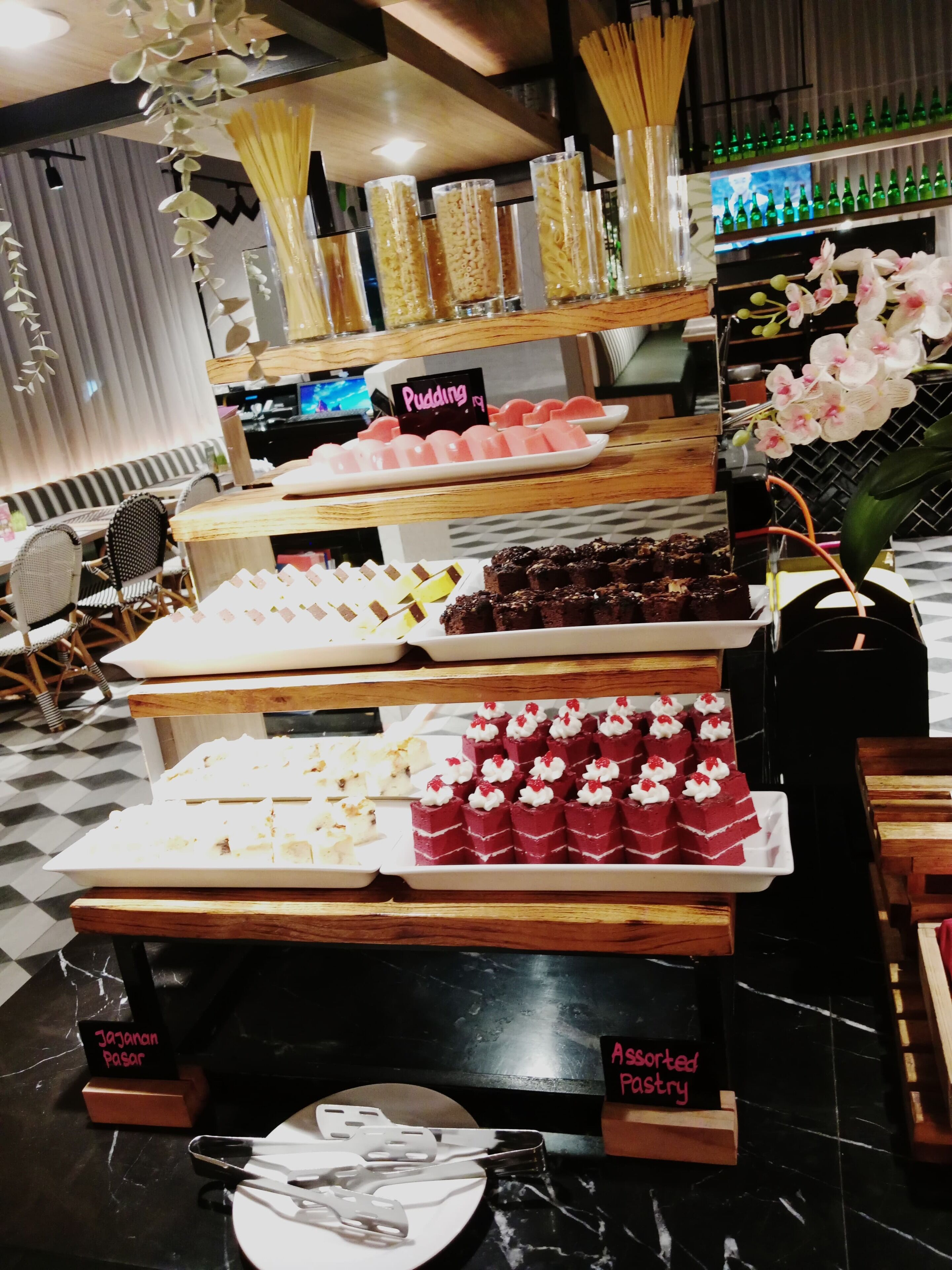 A dessert display with various sweets and a sign indicating 'Pudding' and 'Assorted Pastry'.
