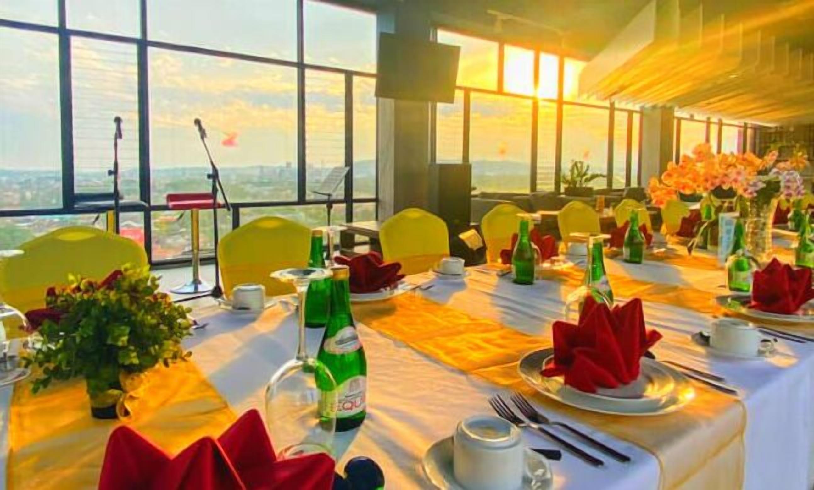 A dining area with tables set for a meal, large windows offering a view, and a stage with musical instruments.