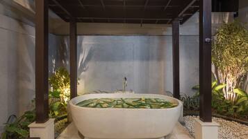 Een aparte badkuip en douche, een diep bad, handdoeken, zeep