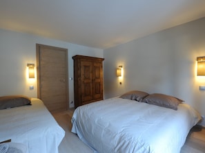Habitación de hotel con dos camas, un armario e iluminación en la pared.
