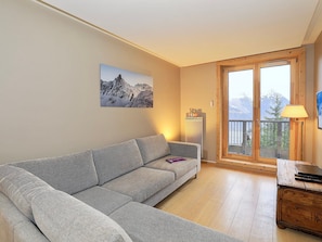 A living room with a grey sofa, a wooden coffee table, a lamp, and a large window with a view of mountains. - Elegant apartment in Courchevel Village, 3 bedrooms, pets allowed (Courchevel 1550)