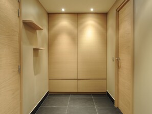 Un pasillo con puertas de madera y suelo de baldosas.