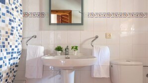 Un baño con un lavamanos blanco, dos plantas en macetas, un espejo y un inodoro.