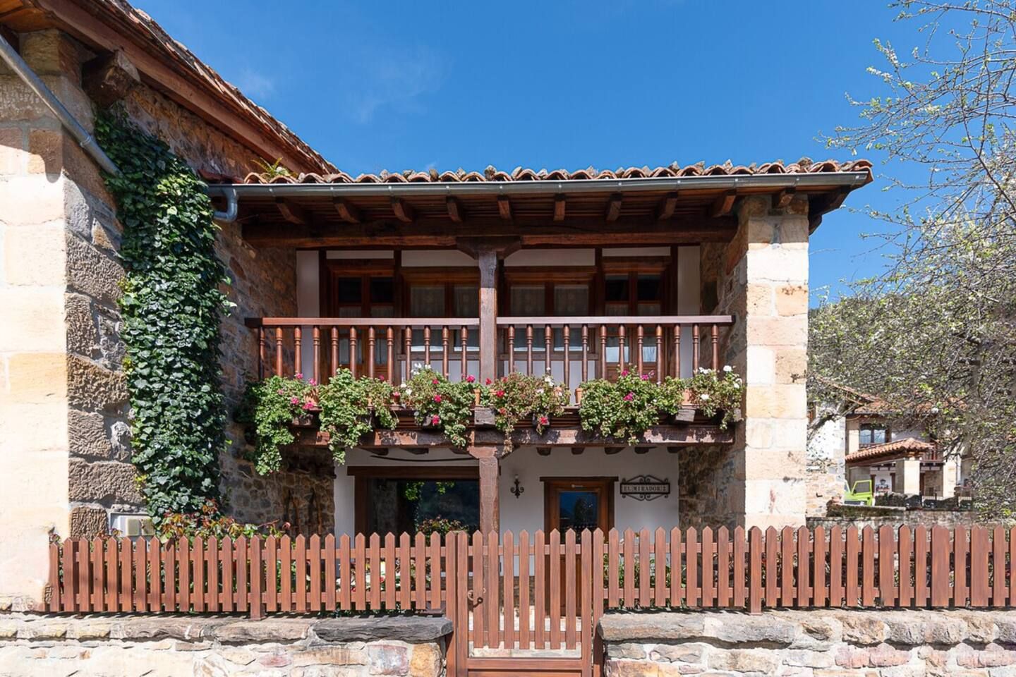 Un bâtiment traditionnel doté d’un balcon en bois, de murs en pierre et d’une clôture en bois.