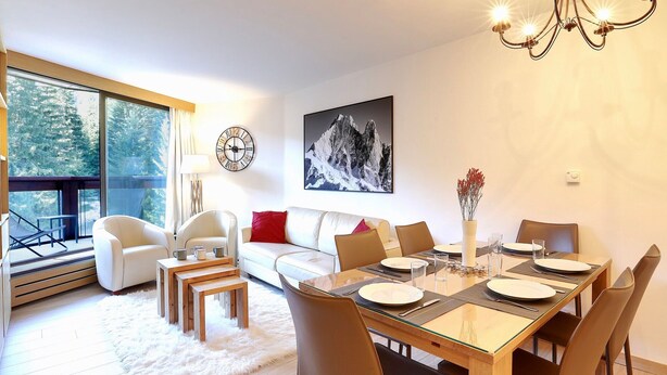 Uma sala de jantar moderna com mesa de vidro, cadeiras de madeira e um lustre.