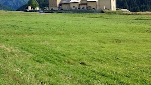 A rural building with a stone tower, surrounded by a green field and mountains in the background. - IN NEED OF FRESH AIR, NATURE AND CALM? (Molines-en-Queyras)