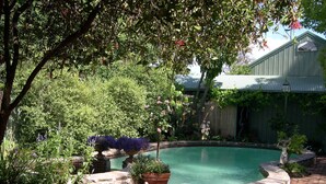 Una piscina rodeada de vegetación exuberante y un edificio rústico al fondo.