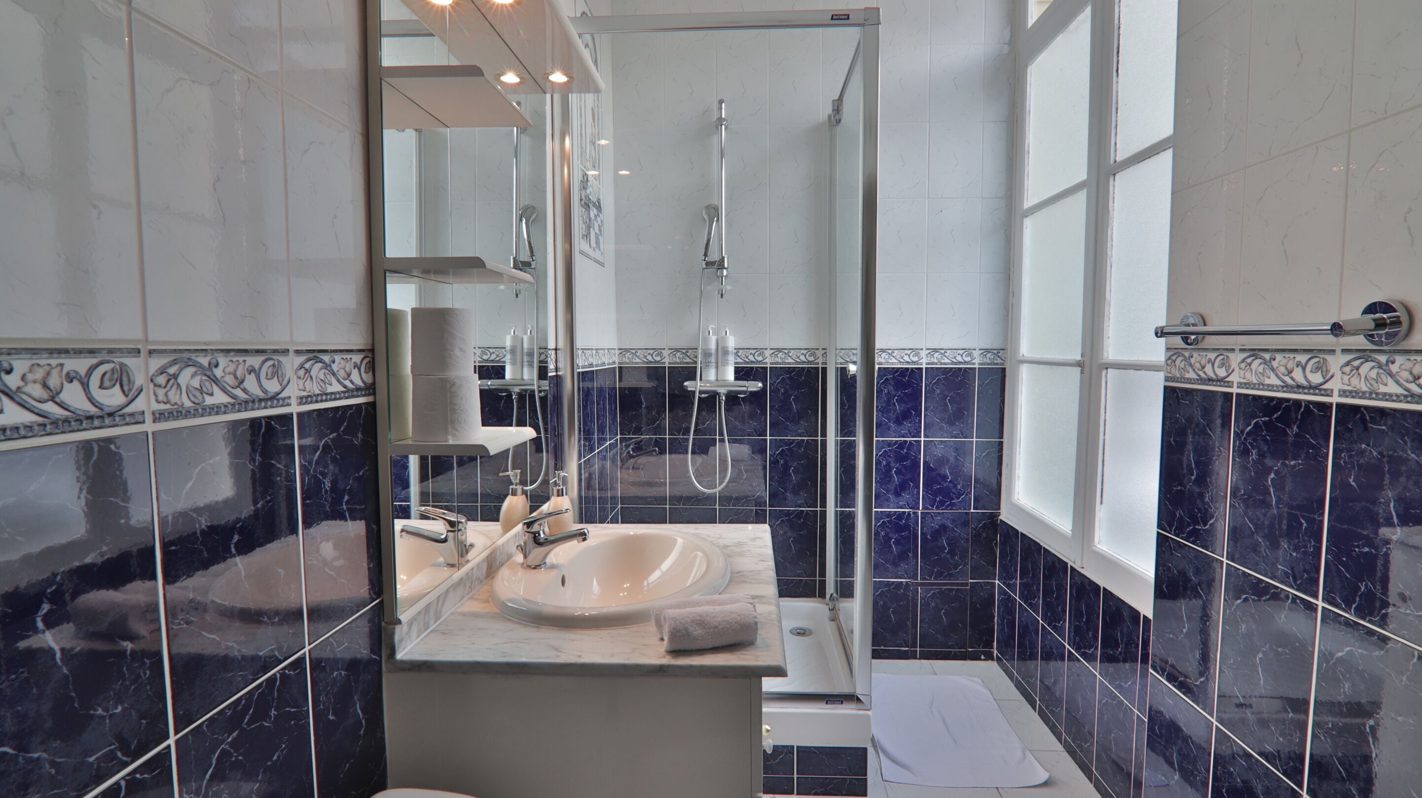Un baño con lavabo, espejo, ducha y ventana.
