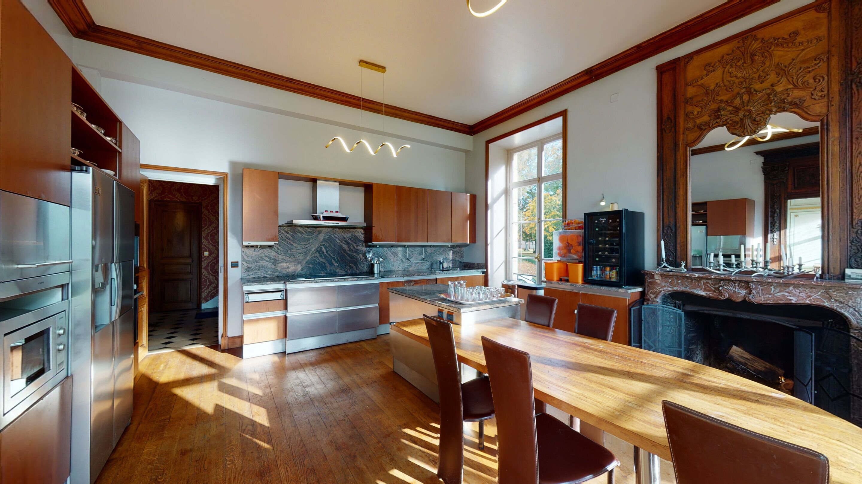 Una cocina moderna con una isla central, armarios de madera y un salpicadero de mármol.