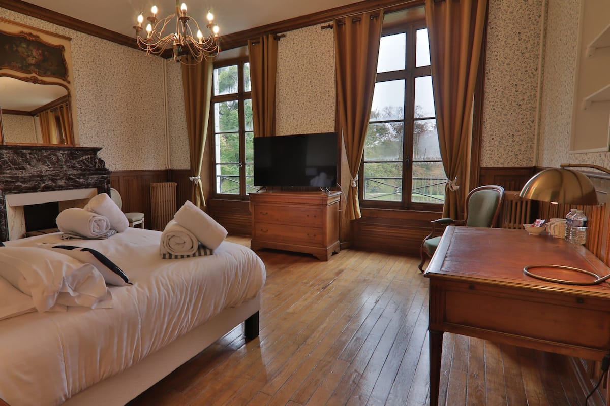A hotel room with a large bed, a television, a desk, and a view of the outdoors.