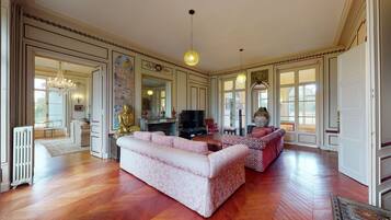 A spacious living room with a large sofa, a television, and a Buddha statue.