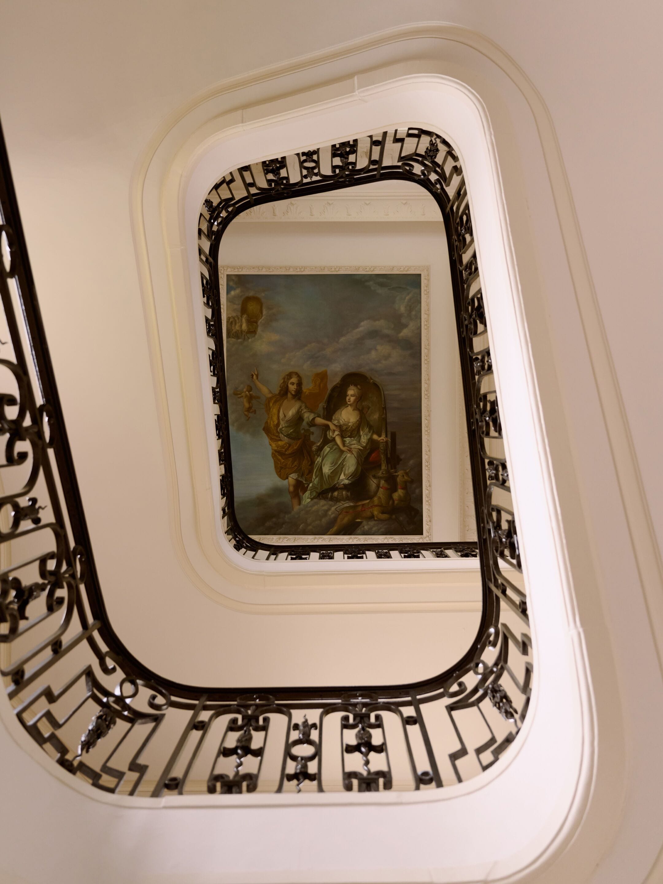 Eine Treppe mit aufwendig gestalteten schwarzen Metallgeländern und einem gerahmten Gemälde von zwei Personen.
