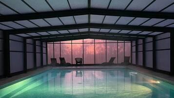 Een binnenzwembad, parasols bij het zwembad en ligstoelen