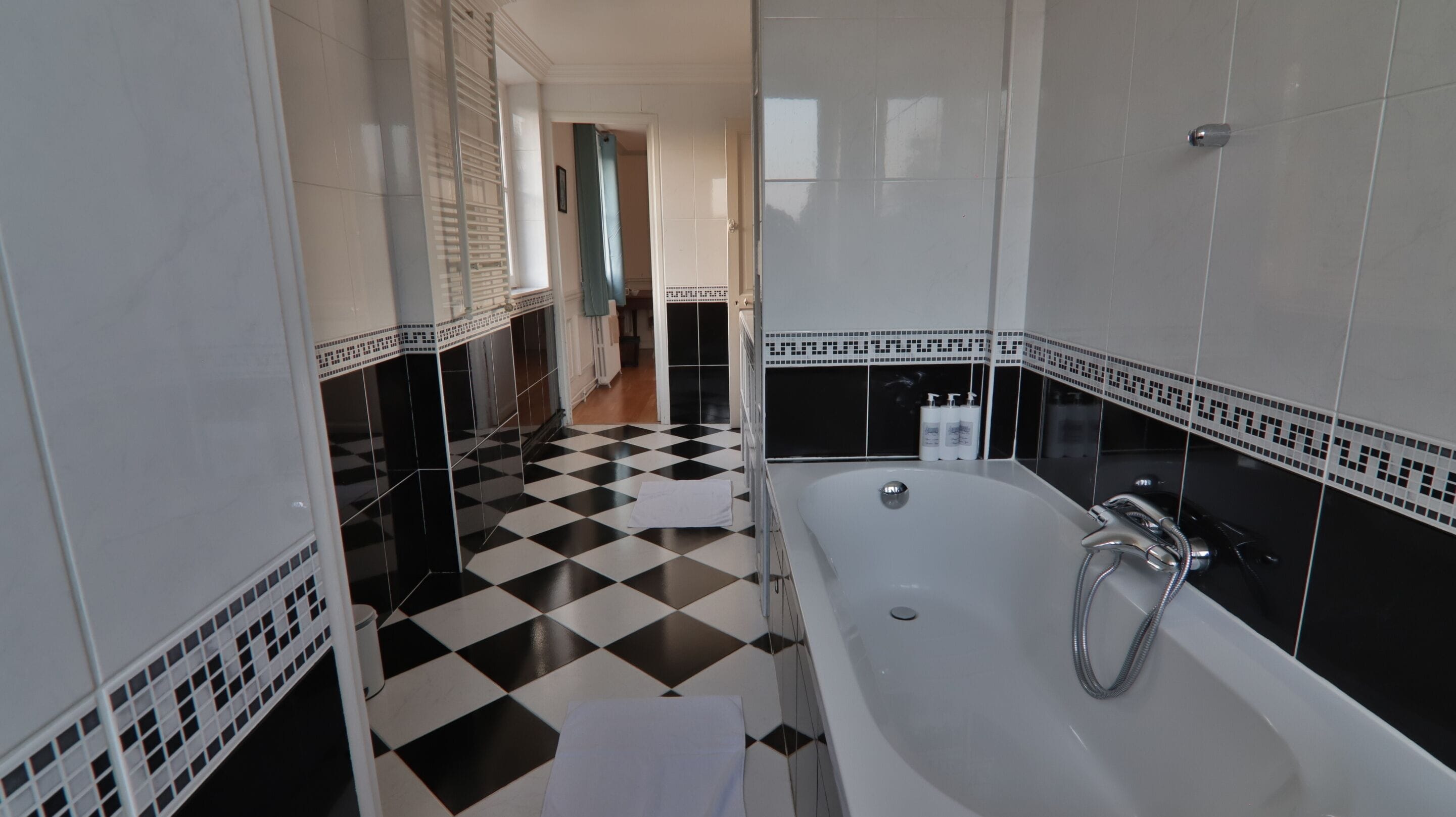 Un baño con piso a cuadros, una bañera y zona de ducha.