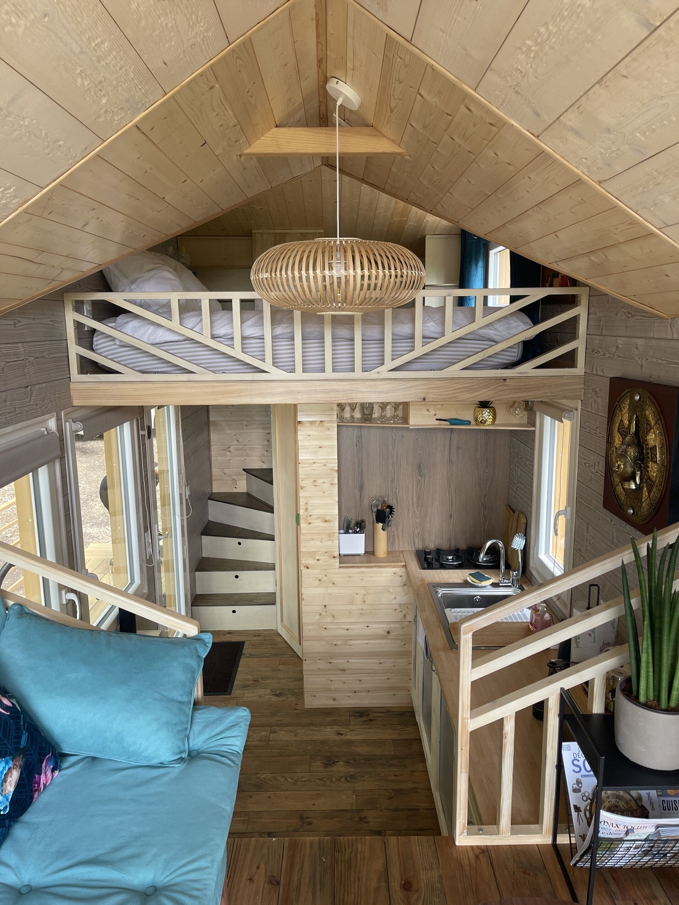 A compact cabin with a loft bedroom, a kitchenette, and a dining area.