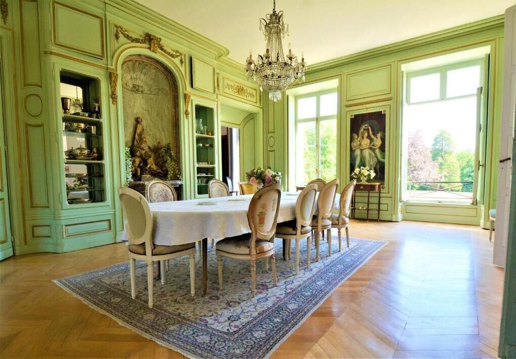 Un comedor con una araña, una mesa dispuesta para seis personas y un ventanal con vistas.