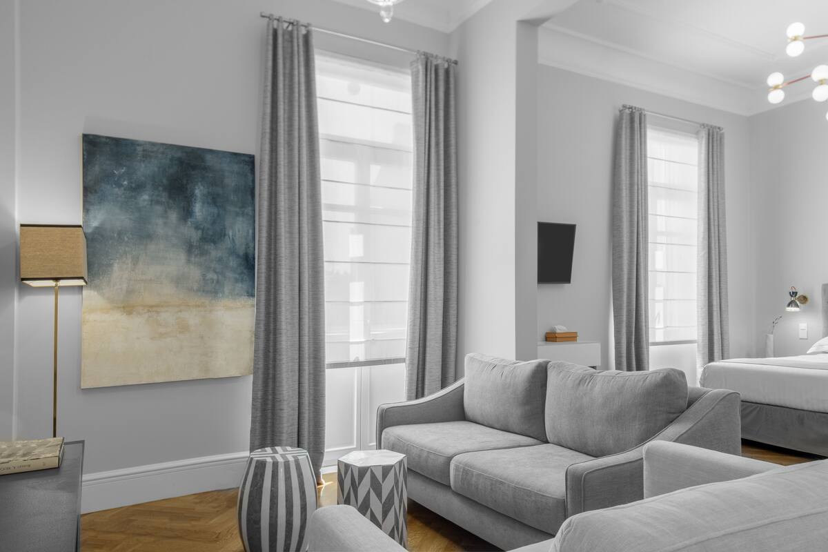 Ein modernes Wohnzimmer mit einem grauen Sofa, einem gestreiften Beistelltisch und einem großen abstrakten Gemälde an der Wand.
