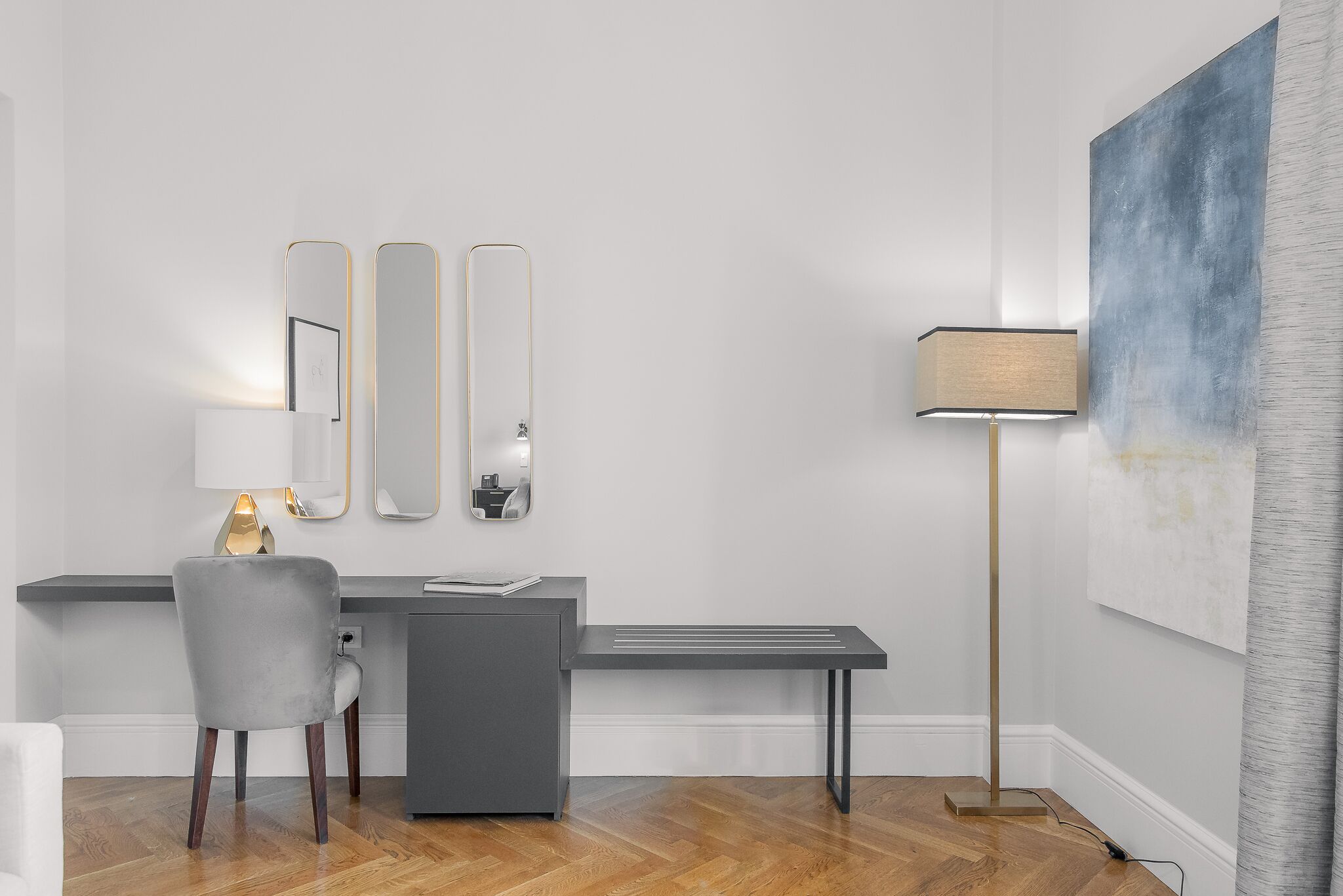 A modern room with a desk, chair, and a large abstract painting on the wall.