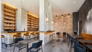 Een modern restaurant met hoge plafonds, een stenen muur en een bar met flessenkasten.