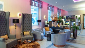 A modern lounge area with tufted armchairs, a bar, and a variety of plants. - Leonardo Royal Hotel Nürnberg (Nuremberg)