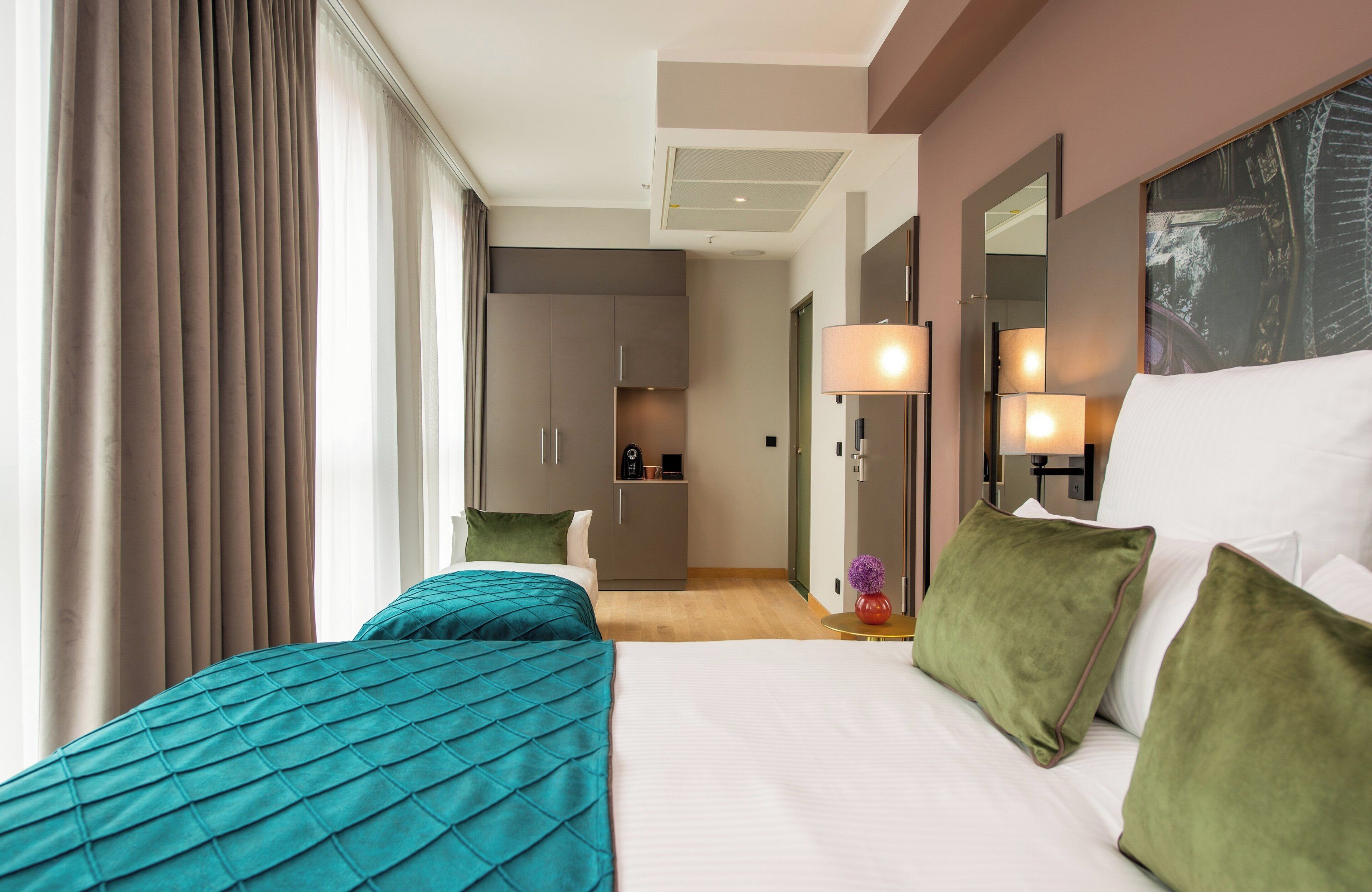 Una habitación de hotel con una cama grande, un escritorio y una kitchenette al fondo.