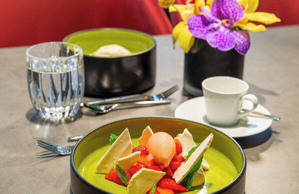 A dining table with a green bowl of soup, a white cup, and a glass of water. - Leonardo Royal Hotel Nürnberg (Nuremberg)
