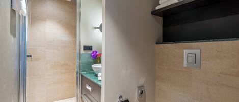 Un baño moderno con cabina de ducha de vidrio, inodoro blanco, tocador con espejo y barra para toallas.