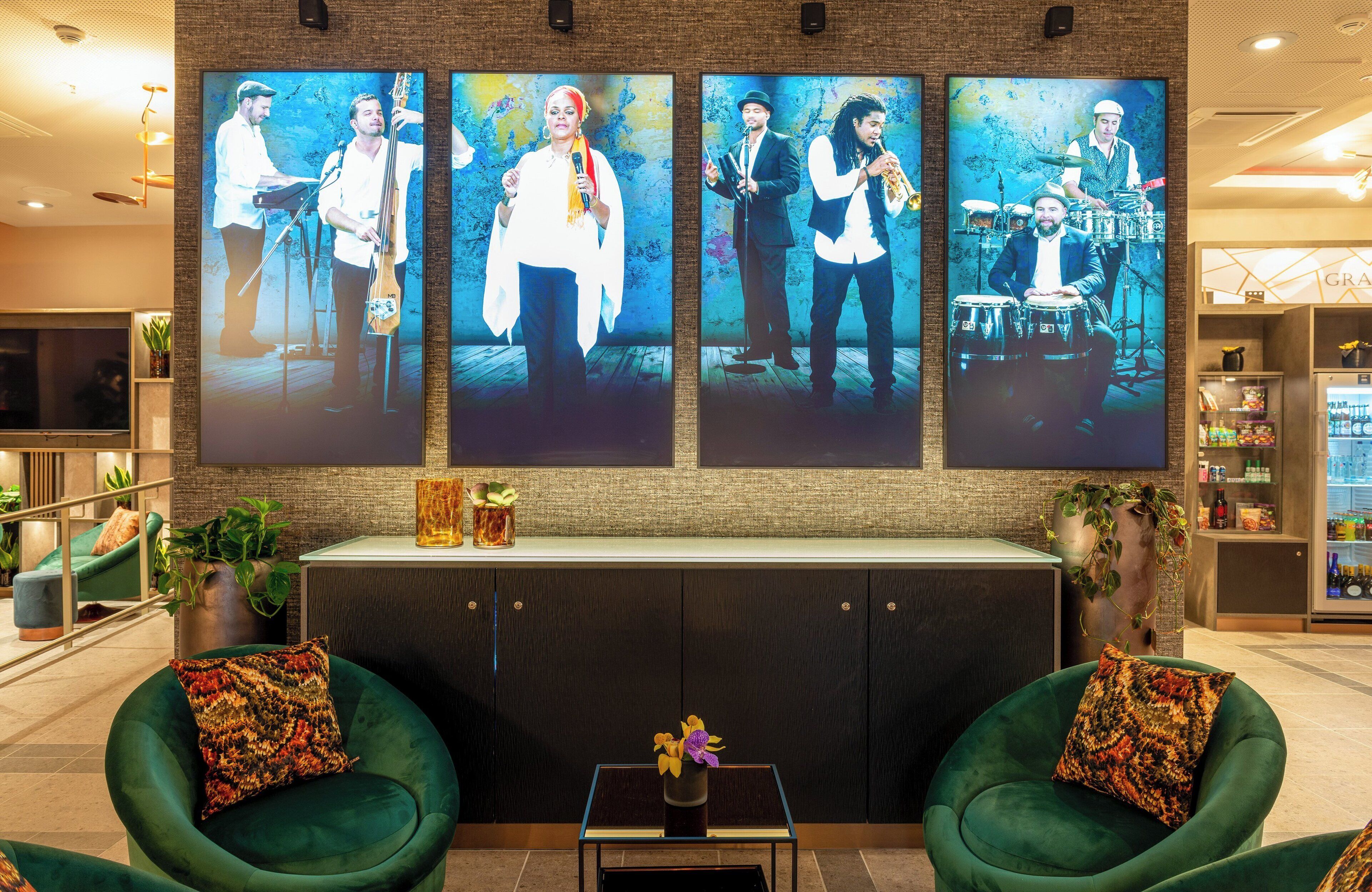 A lobby with green armchairs, a reception desk, and a large wall with framed photographs of musicians.