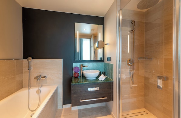 A modern bathroom with a bathtub, a glass-enclosed shower, a vanity with a sink, and a mirror.
