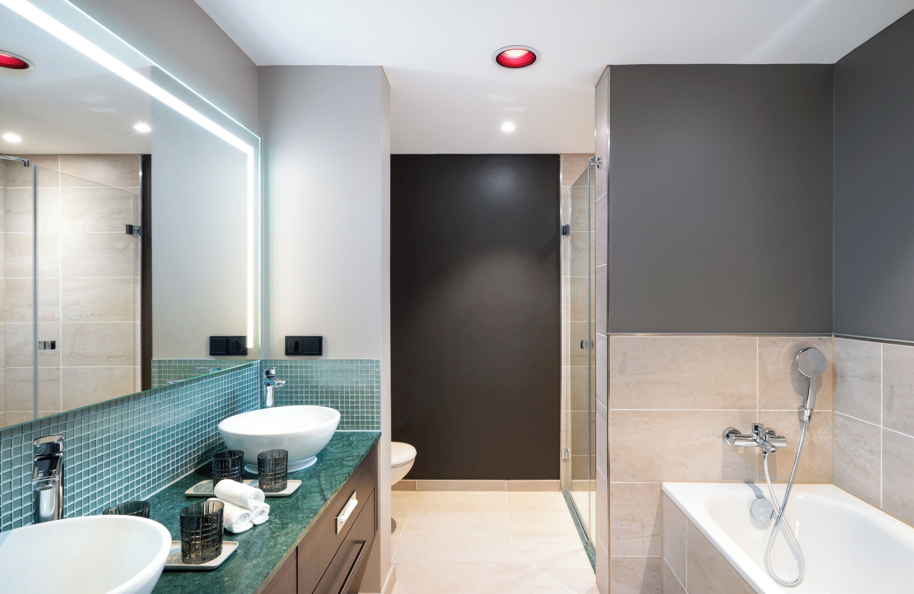 Een moderne badkamer met twee wastafels, een douche en een grote spiegel.
